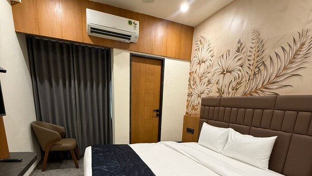 Une chambre d’hôtel équipée d’un lit, d’une chaise, d’un bureau, d’un appareil de climatisation et d’une porte.