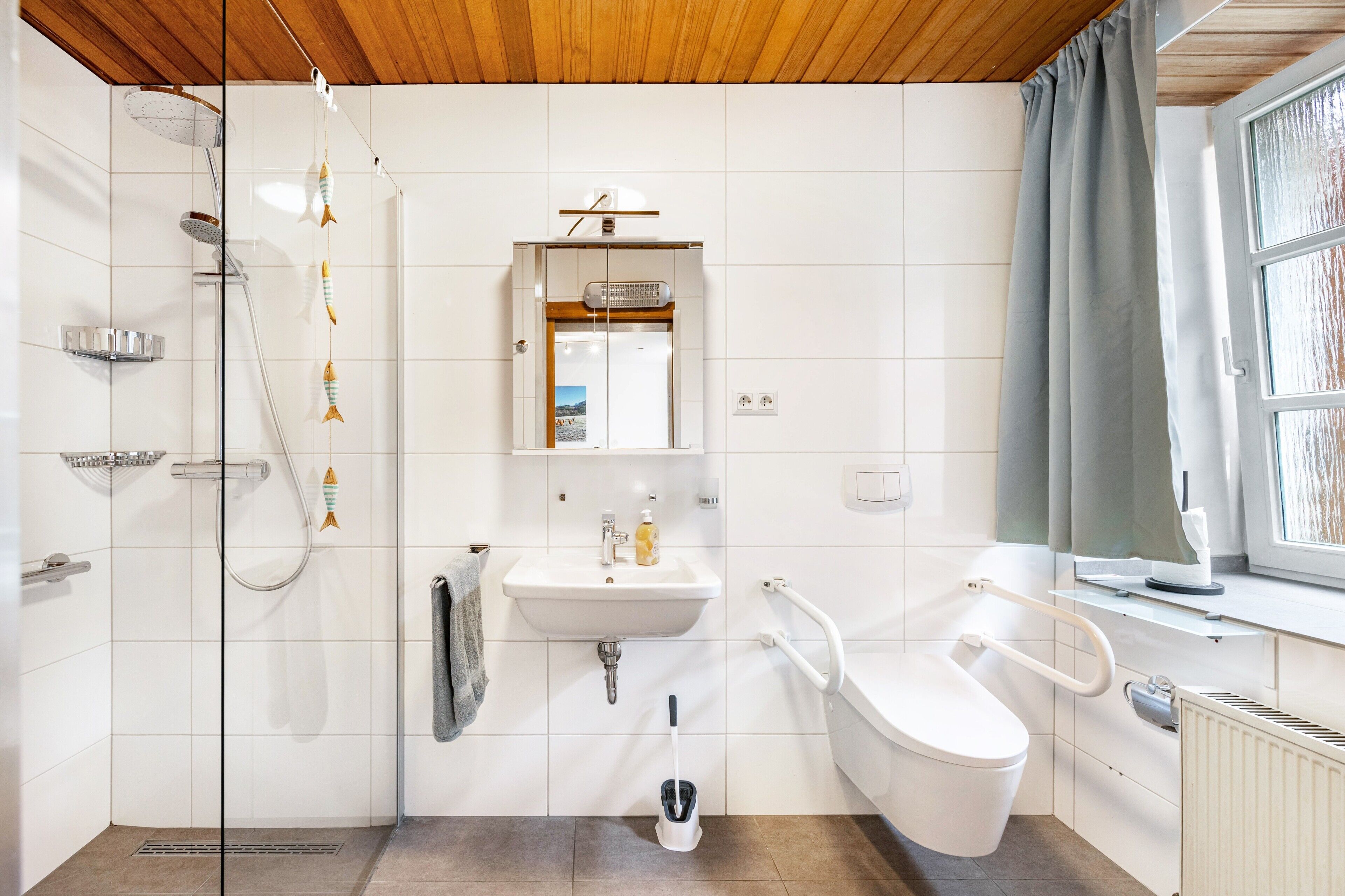 Une salle de bain moderne équipée d’une douche, d’un lavabo, de toilettes et d’une fenêtre avec des rideaux.