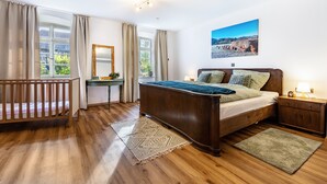 Ein Schlafzimmer mit einem Holzbett, einem Schreibtisch, einem Spiegel und Blick ins Freie.