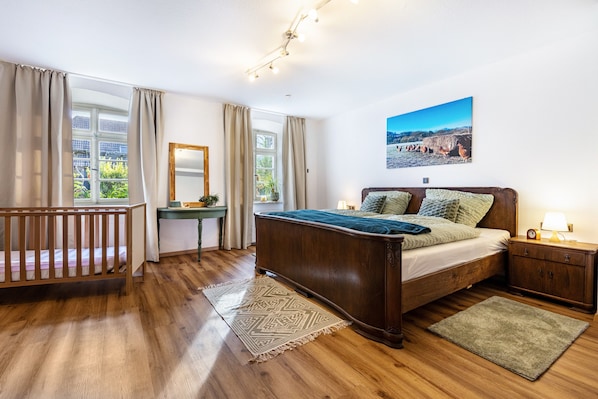 Une chambre à coucher avec un lit en bois, un bureau, un miroir et une vue sur l’extérieur.