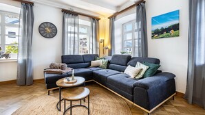 Ein modernes Wohnzimmer mit einer Eckcouch, einem runden Couchtisch und einer Wanduhr.