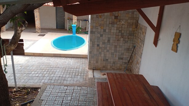 Un espace extérieur abrité comprenant une piscine, un banc en bois et un mur recouvert de carreaux.