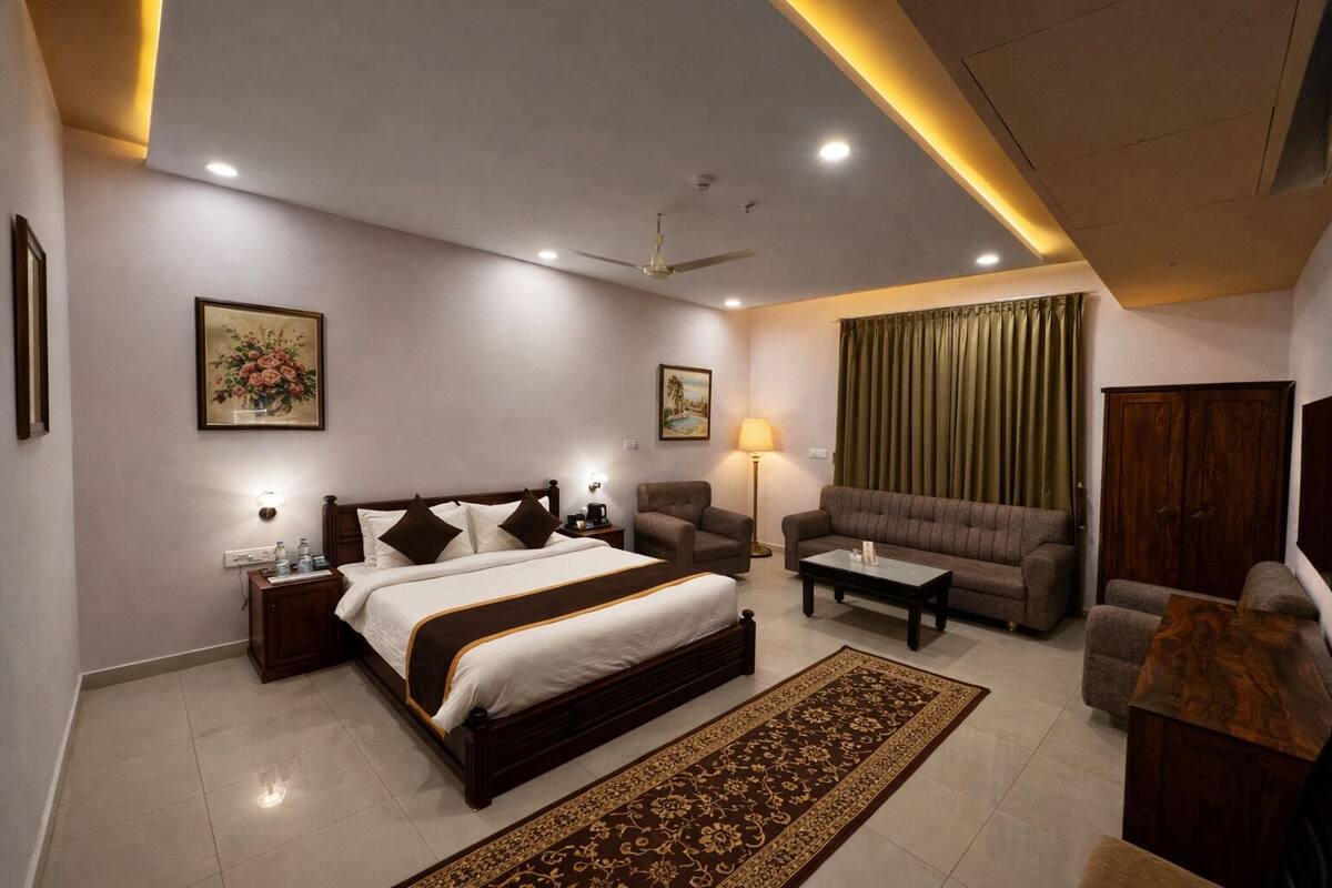 Une chambre d’hôtel moderne comprenant un grand lit, deux fauteuils, un canapé, une table basse, un bureau et une armoire.