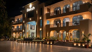 A multi-story building with a prominent 'Daksh' sign, featuring balconies, arched windows, and outdoor seating areas with potted plants. - Daksh The Fateh Retreat - Udaipur (Udaipur)