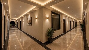 A long, well-lit corridor with a polished floor, wall-mounted lights, and framed artwork. - Daksh The Fateh Retreat - Udaipur (Udaipur)