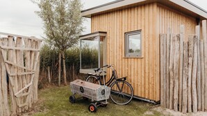 A wooden cabin with a bicycle and a wagon. - Solglimt 2 Pers Holiday Home With Stunning Views (Callantsoog)