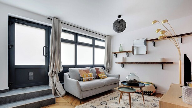 A modern living room with a grey sofa, a coffee table, and a large window with curtains. - Cosy Apartment - 1br/4p - Near Nation (Paris)