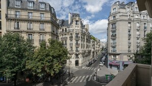Vista de una calle con edificios históricos, un paso de peatones y coches estacionados.