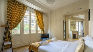 Habitación de hotel con cama, televisión, armario y ventana con cortinas.