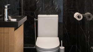 Un baño moderno con inodoro, lavamanos y una cita enmarcada en la pared.