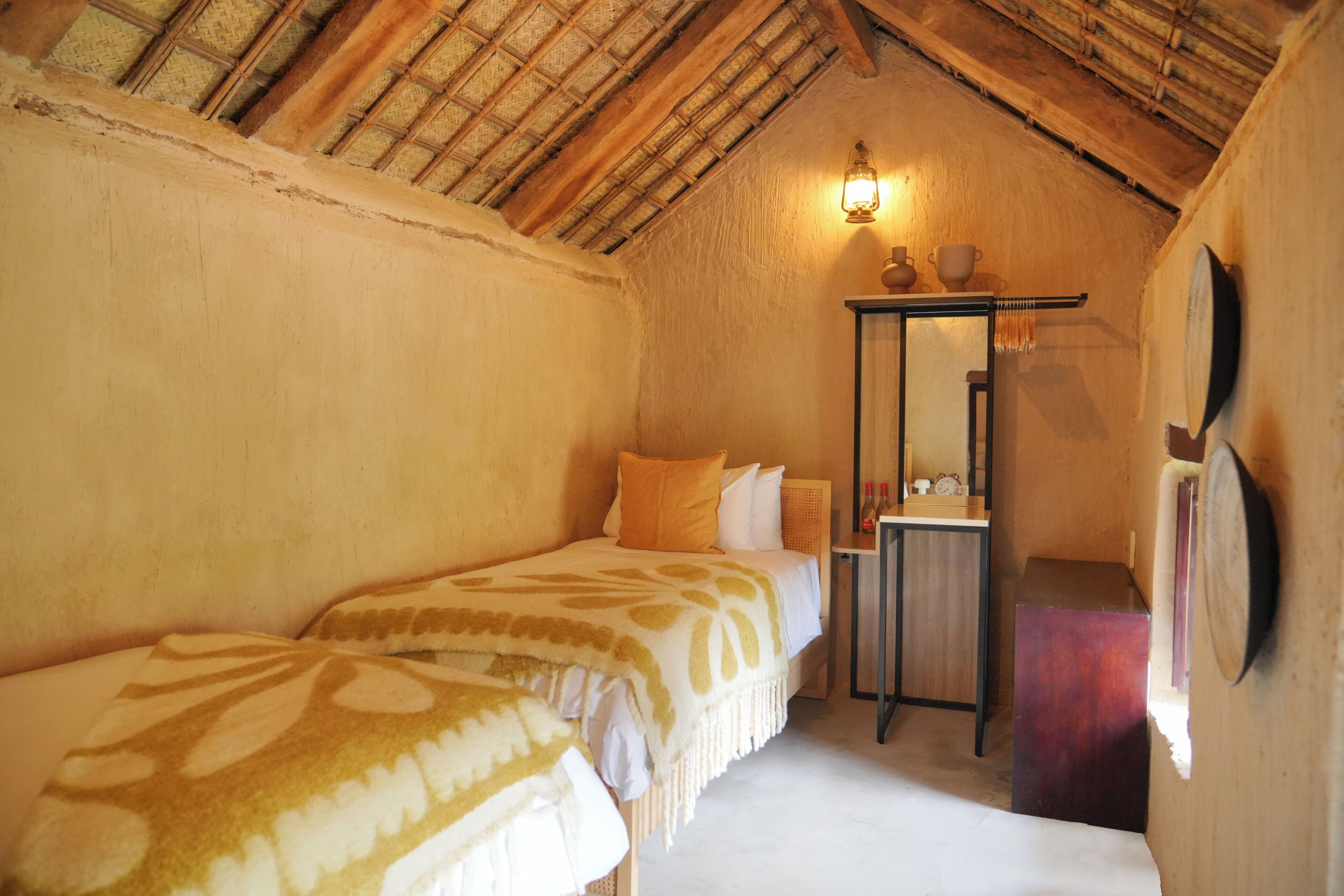 A cozy room with a sloped ceiling, a bed with patterned bedding, a bedside table with a lamp, and a mirror on the wall.