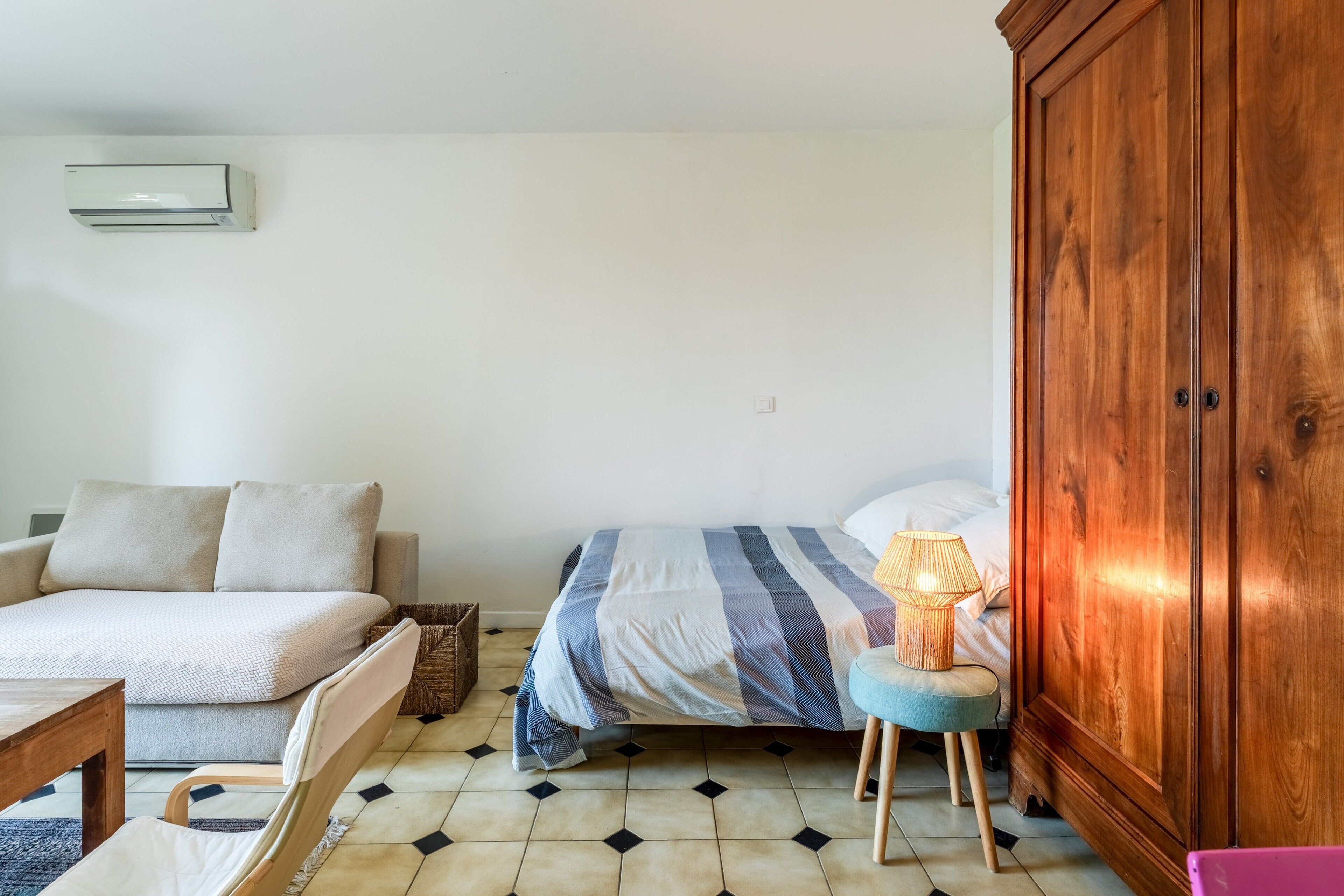 Ein Zimmer mit einem Bett, einem Schlafsofa, einem Holzschrank, einem kleinen Tisch und einer Lampe.