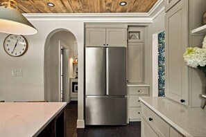A kitchen with a stainless steel double-door refrigerator, white cabinetry, a wooden ceiling, and a clock on the wall. - Homestead Retreat (Salisbury)