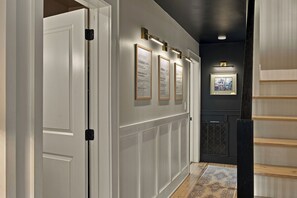 A hallway with white paneled walls, framed artwork, and a black radiator. - Homestead Retreat (Salisbury)