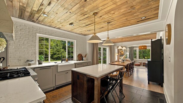 A modern kitchen with a central island, white cabinetry, and a wooden ceiling. - Homestead Retreat (Salisbury)
