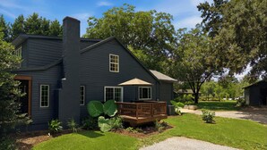 A two-story house with a deck, surrounded by a well-maintained lawn and large trees. - Homestead Retreat (Salisbury)