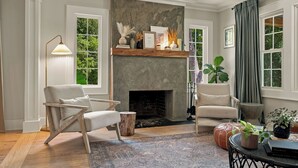 A living room with a fireplace, two armchairs, a floor lamp, and a large window with curtains. - Homestead Retreat (Salisbury)