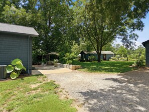 Een woonhuis met een grindpad, een overdekt terras en een klein huis met een tuinhuis.
