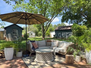 Um pátio externo com um sofá seccional, uma mesa redonda e um guarda-sol grande.