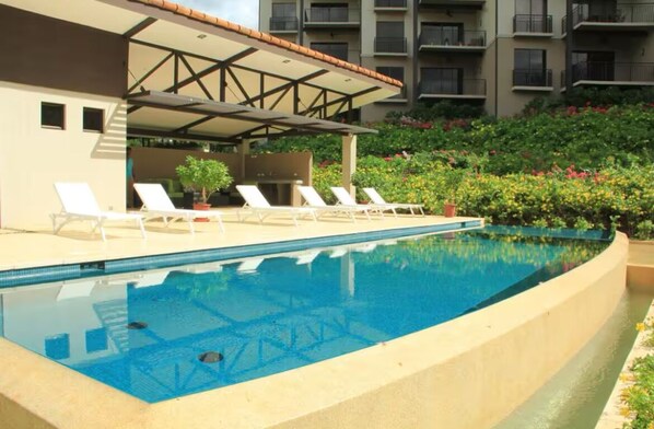 A swimming pool with lounge chairs and a covered area, surrounded by greenery and a multi-story building. - Luxury condo with ocean view at Reserva Conchal, Costa Rica.
Pet-Friendly! (Santa Cruz)