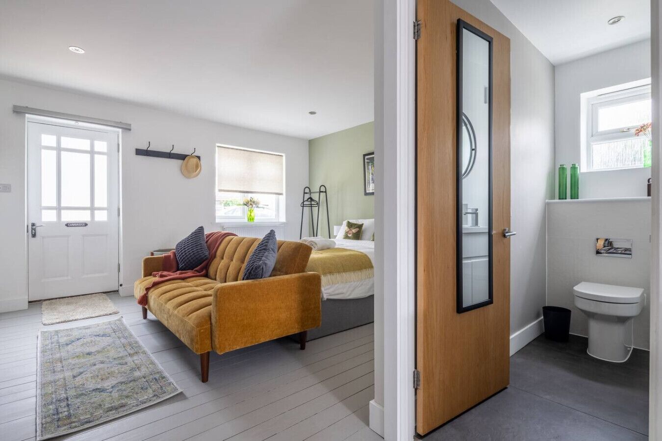 Une chambre moderne avec un canapé-lit, une table de chevet, un miroir et une fenêtre.