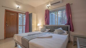 Une chambre à coucher avec un grand lit, deux tables de chevet, une fenêtre avec des rideaux, une porte et un appareil de climatisation.