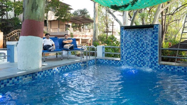 Un espace piscine avec une bordure carrelée, un banc et un arbre peint en blanc et en rouge.