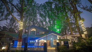 Une maison à l’extérieur bleu, avec une fenêtre ronde et une porte.