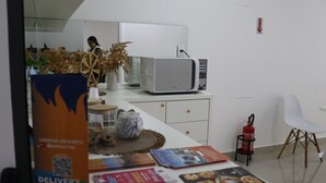 Una cucina moderna con un forno a microonde, una sedia bianca e un estintore.