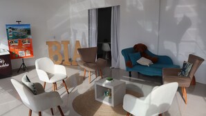 Un soggiorno moderno con poltrone bianche e marroni, un divano blu e un tavolino da caffè con una piccola pianta.