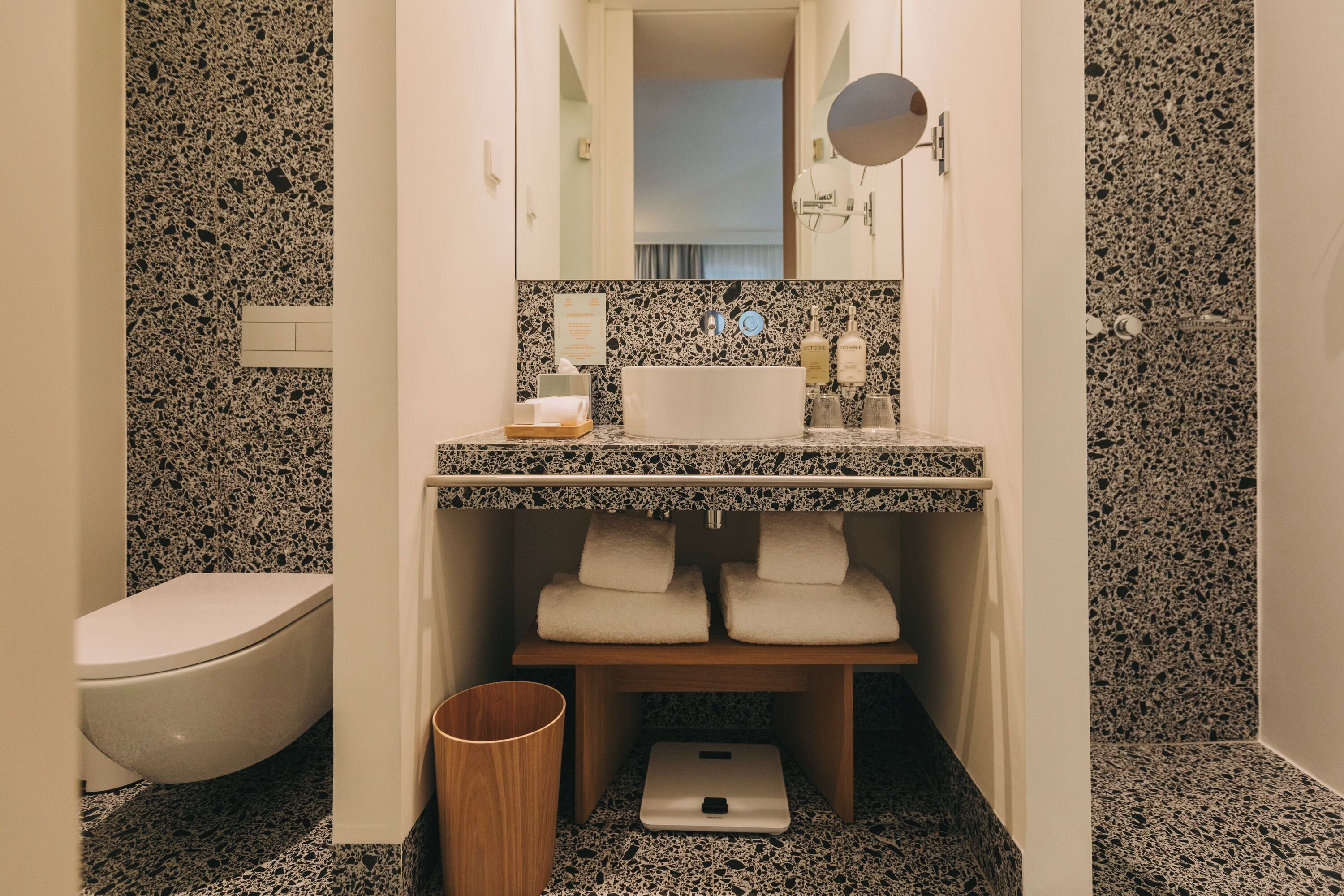A bathroom with a white toilet, a sink with a mirror above, and a scale on the floor.