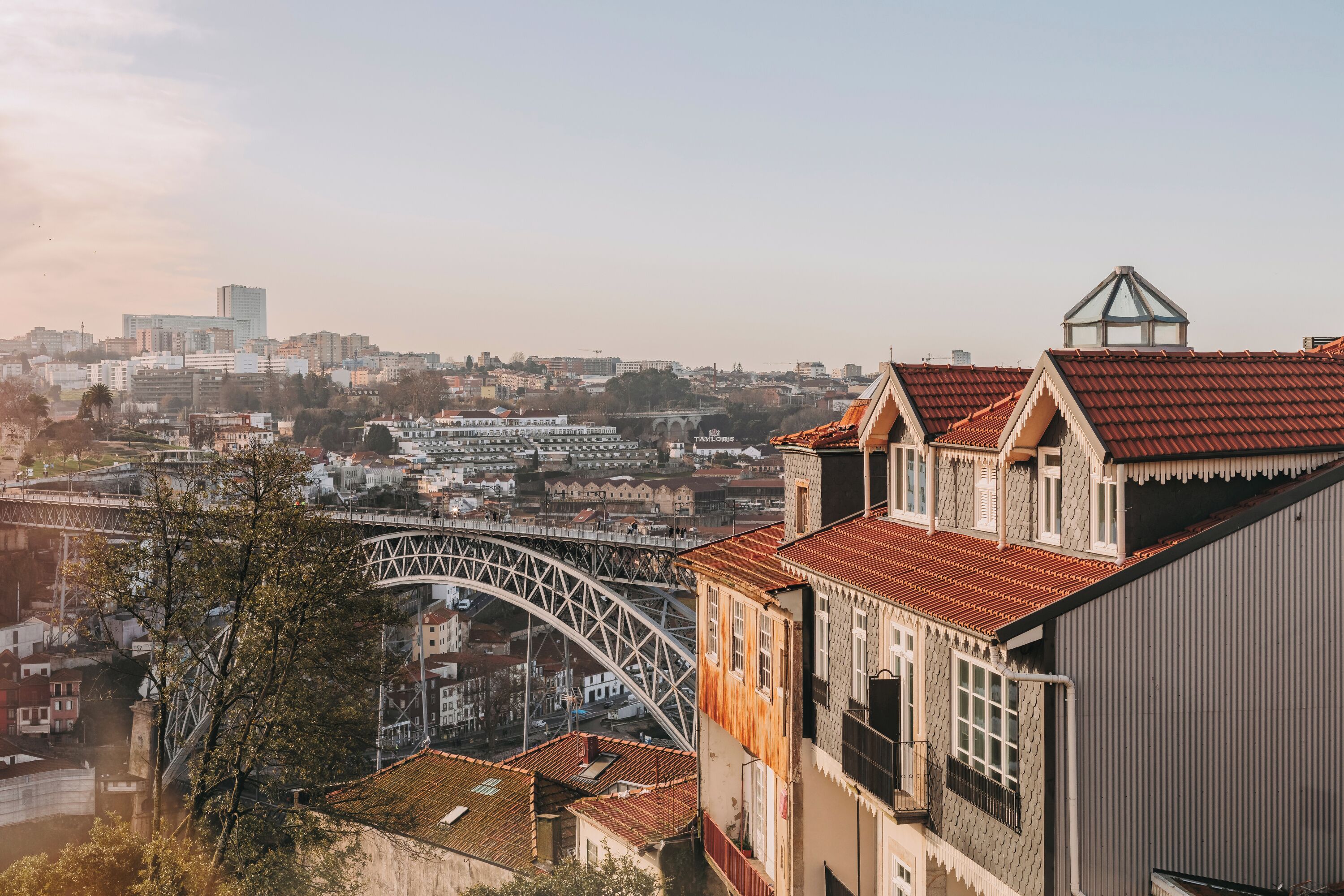 A cityscape with a prominent bridge and traditional buildings with red-tiled roofs.