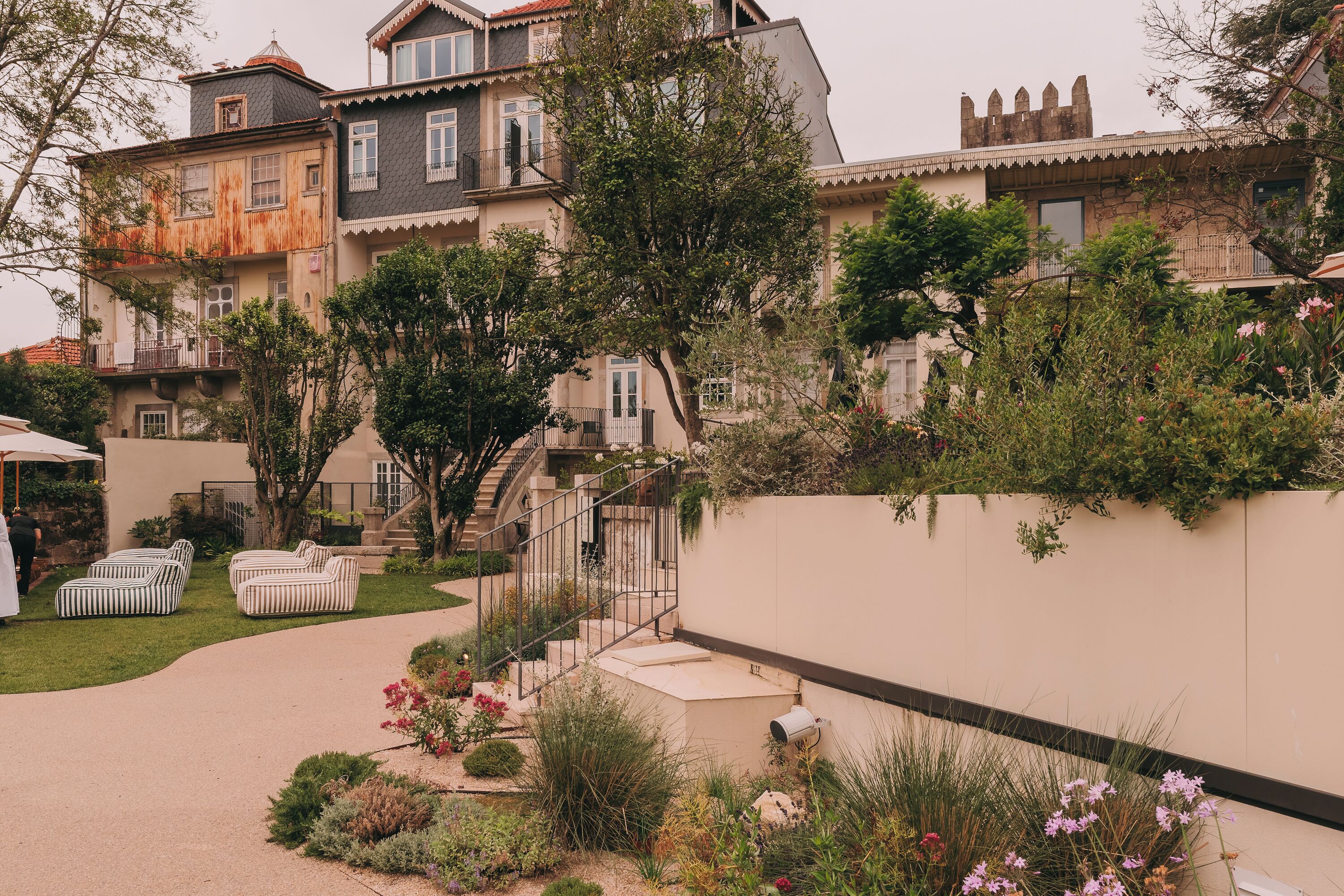 A multi-story building with a garden area, outdoor seating, and a staircase leading to the upper floors.