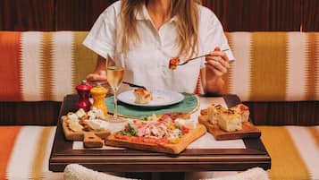 A dining table with various food items and a glass of wine.