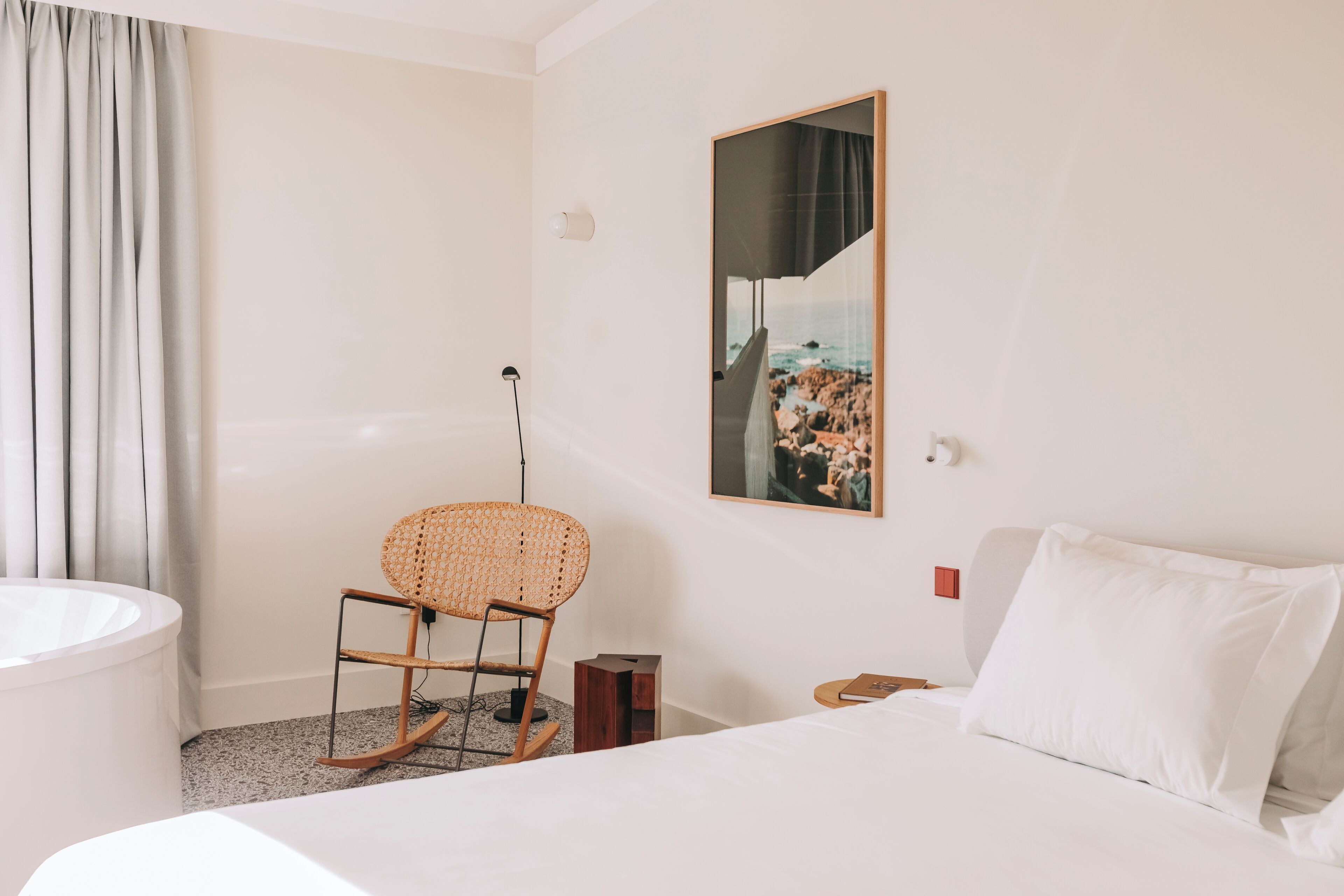 Une chambre d’hôtel avec un lit, une chaise, une baignoire et un tableau au mur.