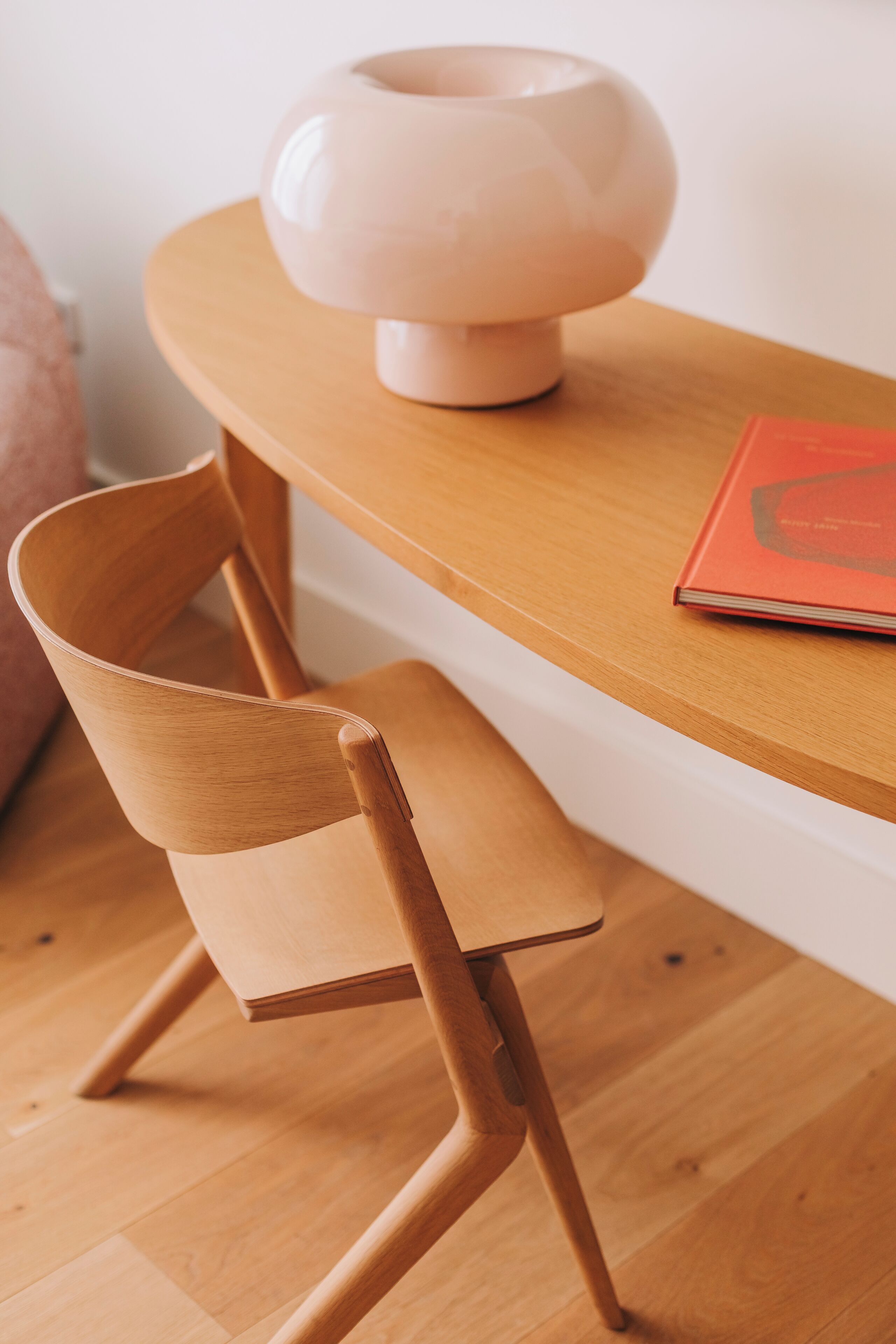 A wooden chair and table with a lamp and a book.