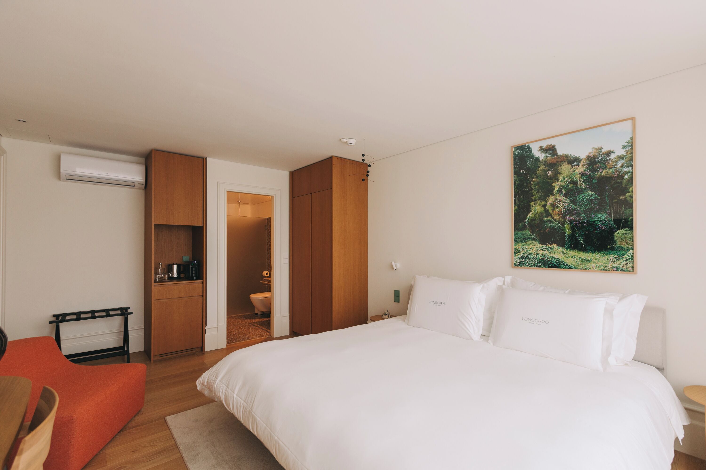 A hotel room with a bed, a desk, a chair, a wardrobe, and a bathroom.