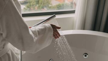 A bathtub with water running, a window with a view of buildings, and a curtain.