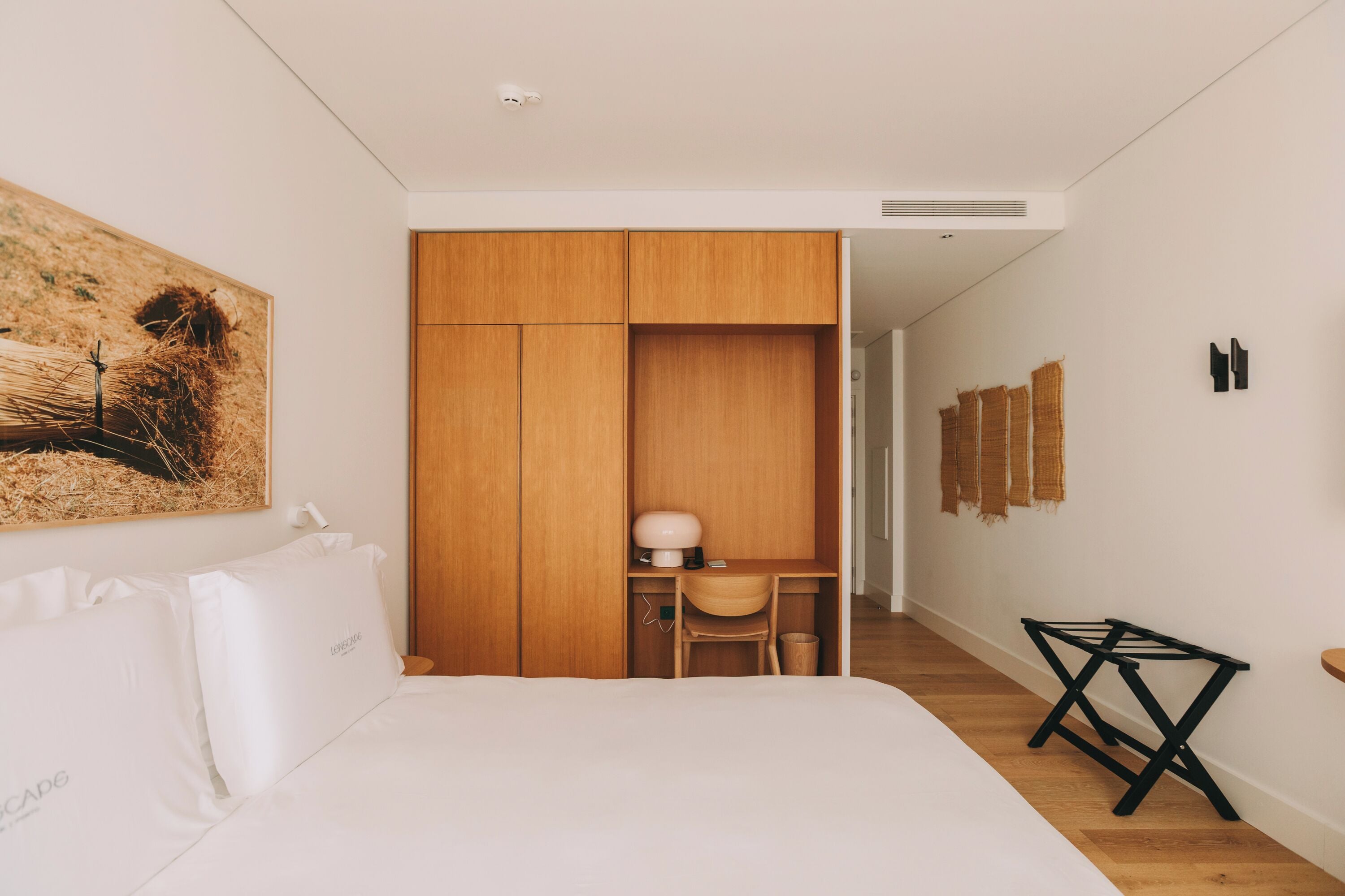 A bedroom with a bed, a desk, and a wardrobe.