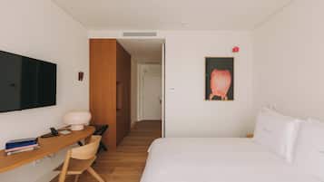 Habitación de hotel con cama, escritorio con silla, televisor de pantalla plana y un cuadro en la pared.