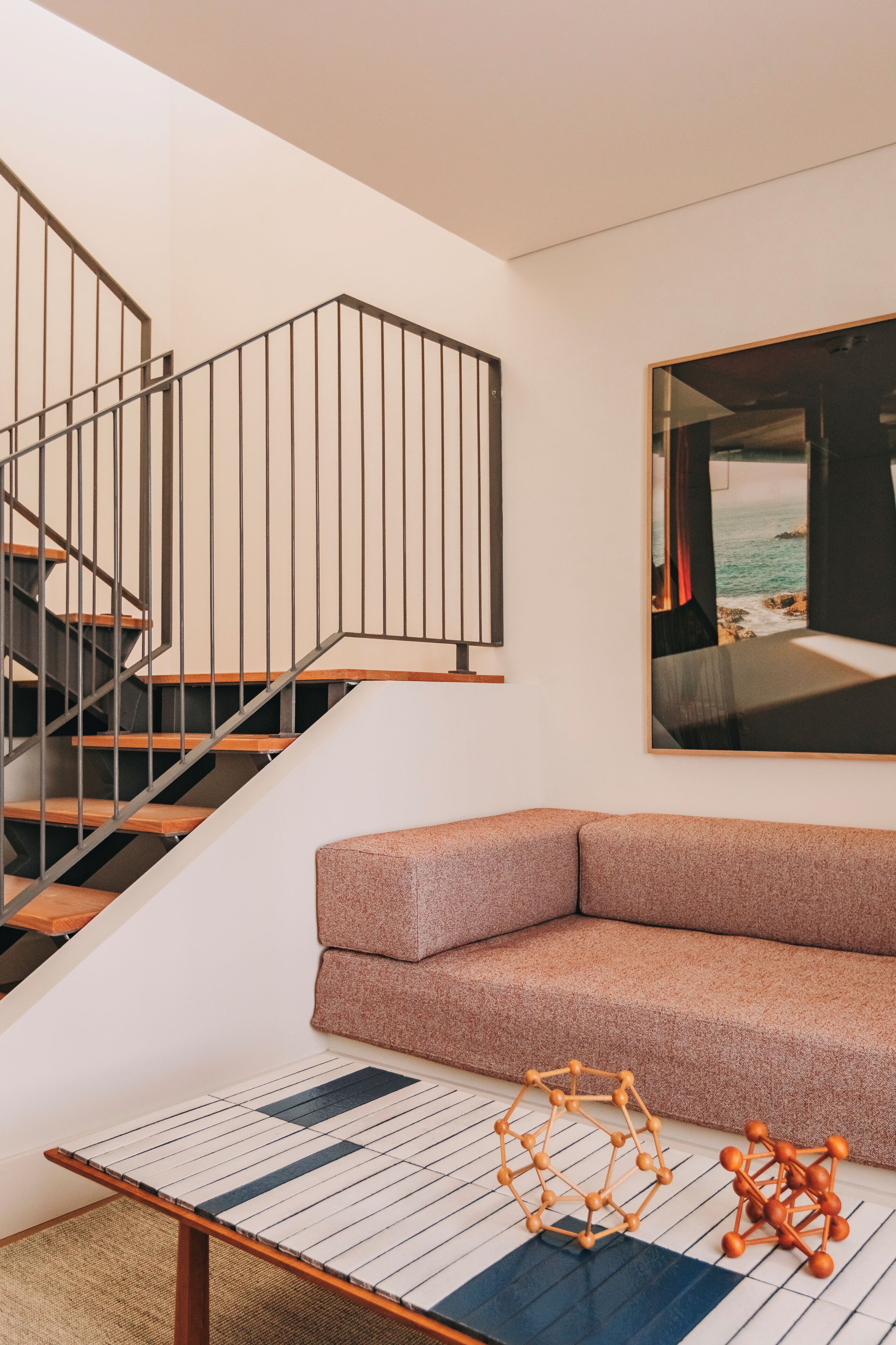 A modern interior with a staircase, a cushioned seating area, and a coffee table with geometric decor.