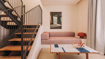Un interior moderno con una escalera, un sofá, una mesa de centro y un cuadro enmarcado en la pared.