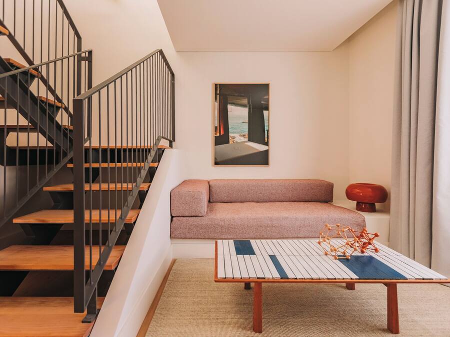 Un interno moderno con una scala, un divano, un tavolino da caffè e un quadro incorniciato appeso al muro.