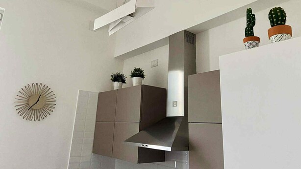 Een moderne keuken met een ingebouwde kookplaat, kasten en een klok aan de muur.