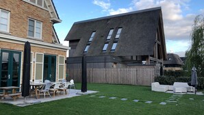 A modern house with a sloped roof, a fenced backyard, and outdoor seating area.