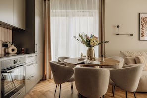 A modern kitchen with a dining area, featuring a round table with chairs, a vase of flowers, and a sofa.