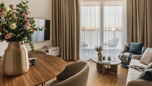 A modern living room with a wooden dining table, a sofa, and a TV. - Electra Apartments by StayLab (Kraków)