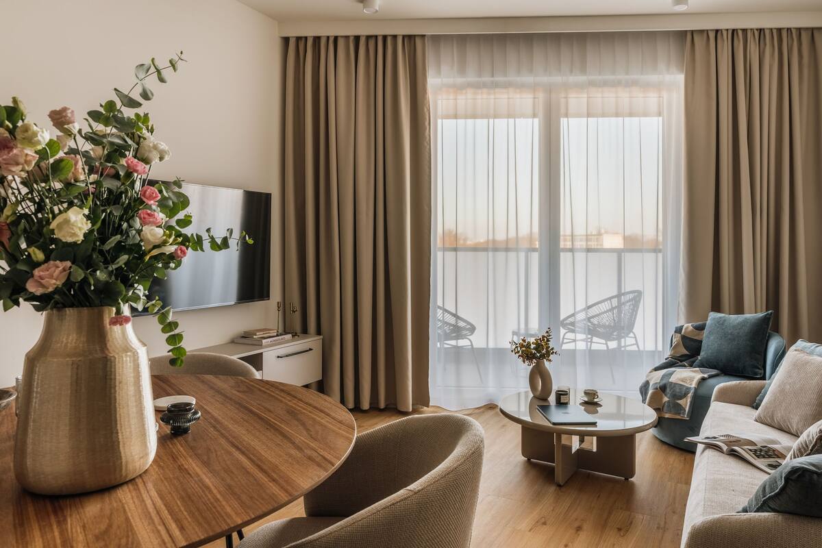 A modern living room with a wooden dining table, a sofa, and a TV.