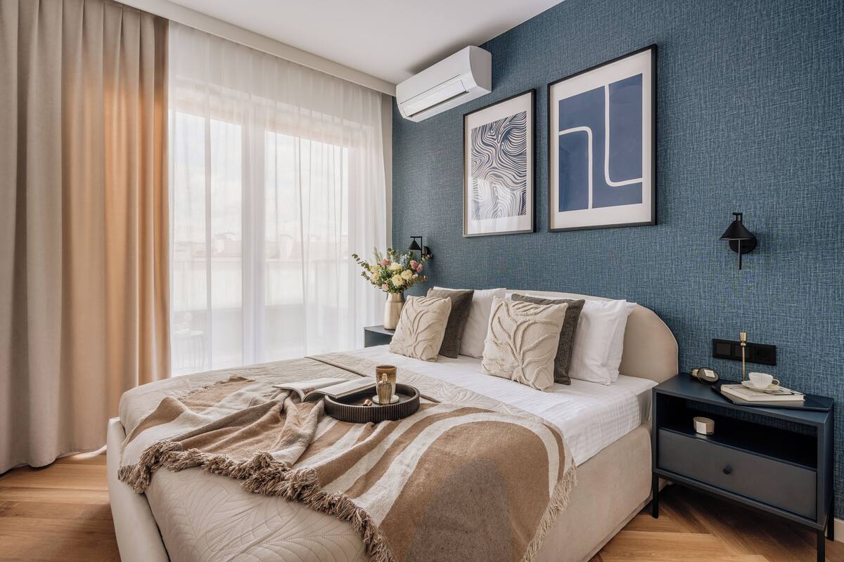 A bedroom with a large bed, a bedside table with a lamp, and artwork on the wall.