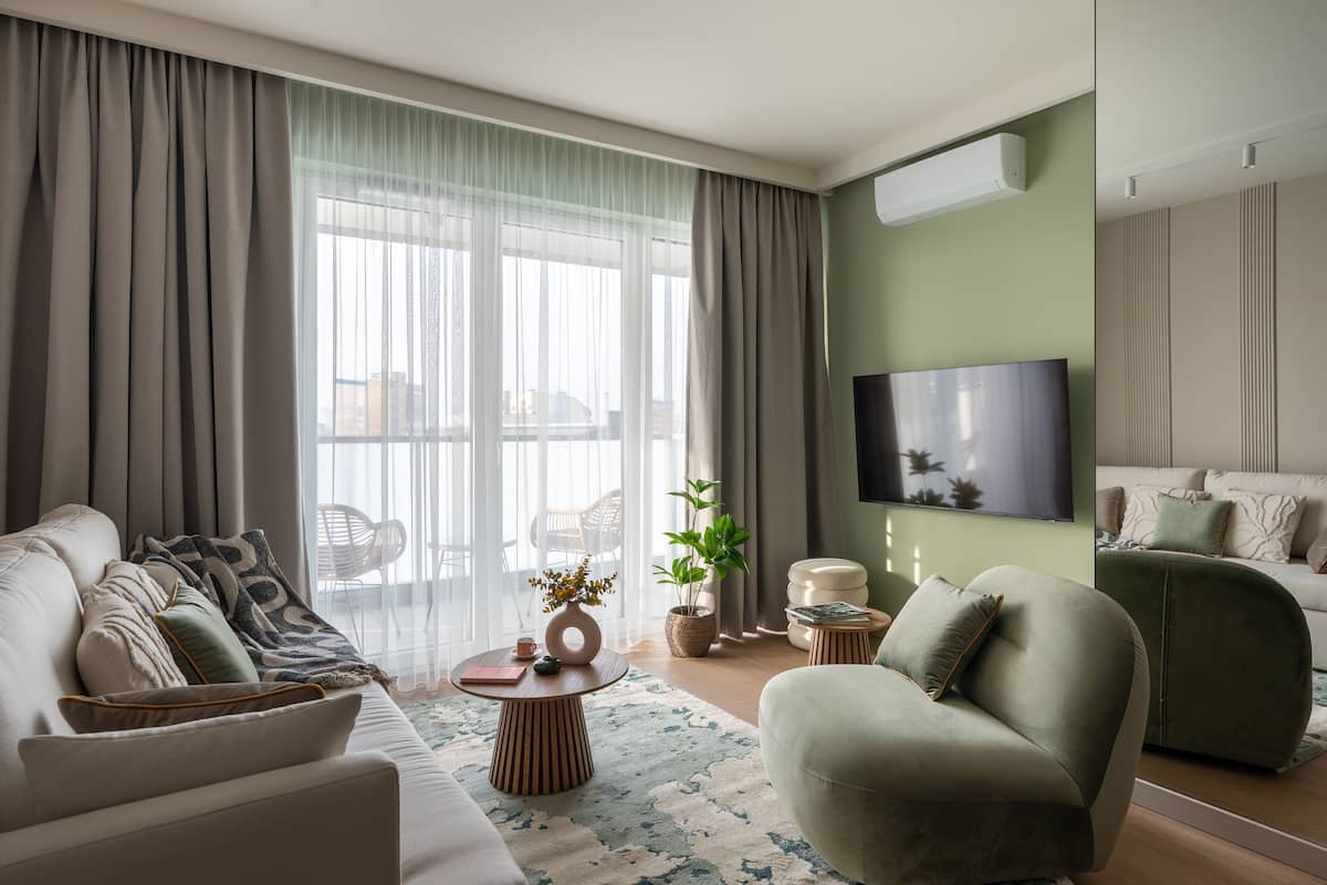 A modern living room with a sofa, armchairs, a coffee table, and a TV.